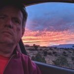 person in car with sunset in background.